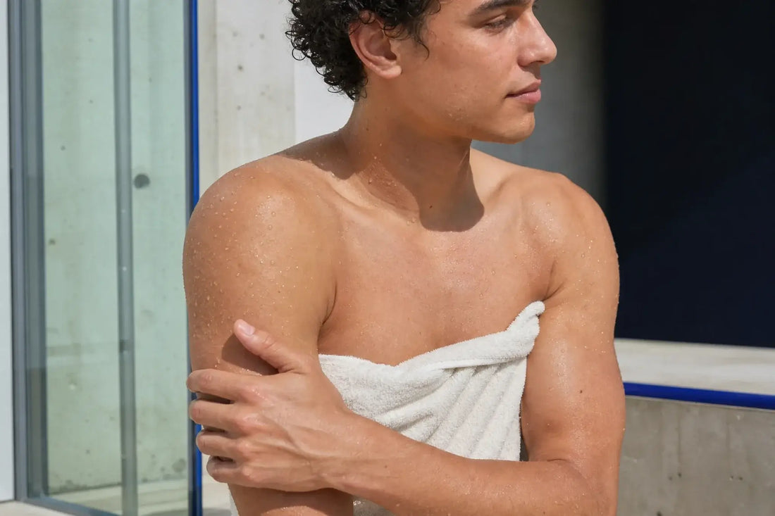 Athletic young adult with a towel and water droplets after a shower for the Shower & Body collection.